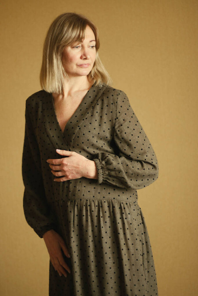 Casual portrait of a happy pensive mature woman with natural white hair and minimal makeup. In a brown cute loose dress. - Foto, Imagem