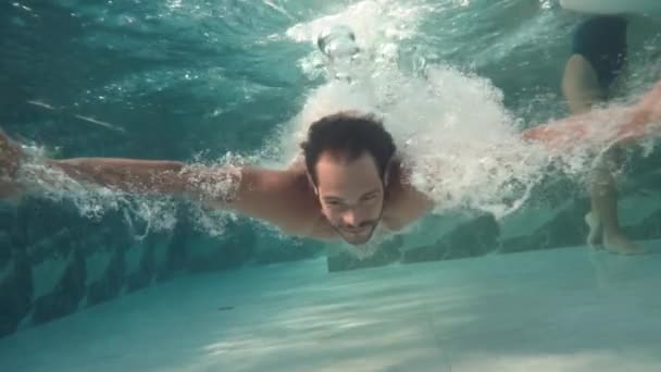 Baixo ângulo de tiro subaquático de homem apto mergulho em água transparente no resort - Filmagem, Vídeo