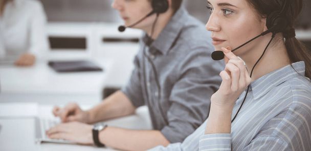 Call center. Group of casual dressed operators at work. Brunette business woman in headset at customer service office - Foto, immagini