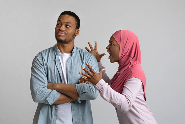 Angry black woman in hijab yelling at her indifferent man - 写真・画像