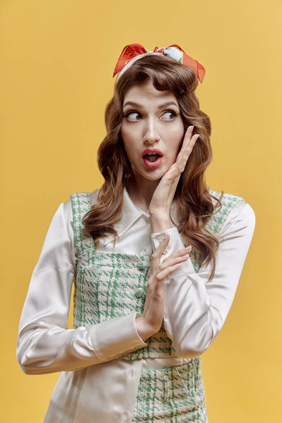 A surprised brunette woman with bright makeup looks away. Yellow background. - Fotoğraf, Görsel