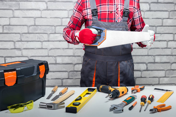  Repairman with hand saw and different tools on the crafting  table. Concept of DIY and home improvement. - Foto, Imagem