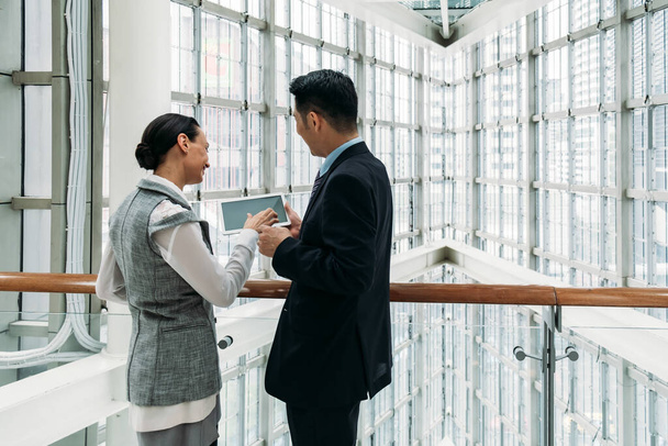 Boldog üzleti csapat két kolléga dolgozik a digitális tablet együtt modern irodai folyosón nagy ablakok - Fotó, kép
