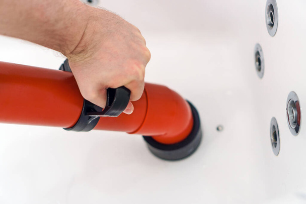 Водопроводчик очищает ванну с помощью профессионального силового насоса. - Фото, изображение