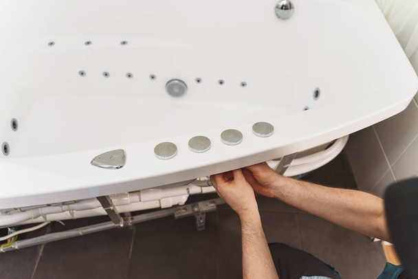 Mann installiert Rohrsystem der Badewanne mit Hydromassage. - Foto, Bild