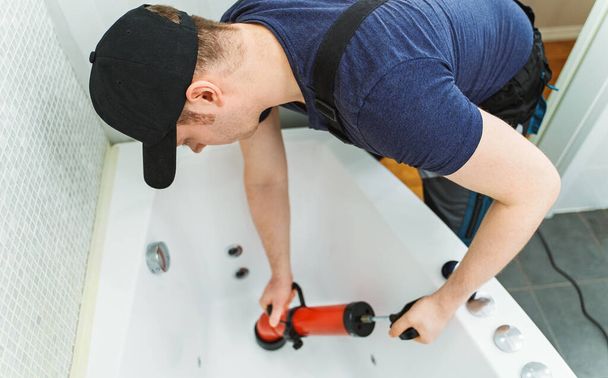 Plumber unclogging bathtub with professional force pump cleaner. - Photo, Image