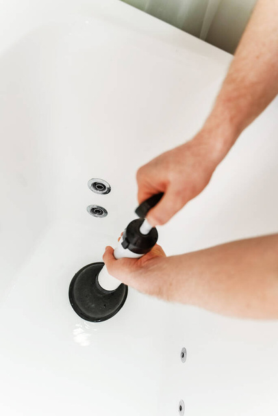 Sanitair ontstoppen badkuip met professionele kracht pomp cleaner. - Foto, afbeelding