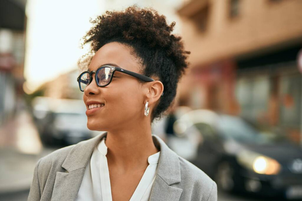 Giovane donna d'affari afroamericana sorridente felice in piedi alla città. - Foto, immagini