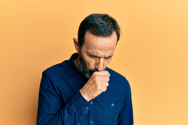 Orta yaşlı İspanyol bir adam günlük kıyafetler giyip kendini kötü hissediyor ve soğuk algınlığı veya bronşitin belirtisi olarak öksürüyor. sağlık hizmeti kavramı.  - Fotoğraf, Görsel