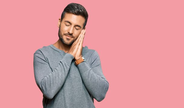 Handsome hispanic man wearing casual clothes sleeping tired dreaming and posing with hands together while smiling with closed eyes.  - Photo, Image