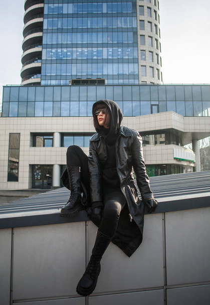 Woman in long leather coat spy agent on the background of a modern building of a business center - Fotografie, Obrázek