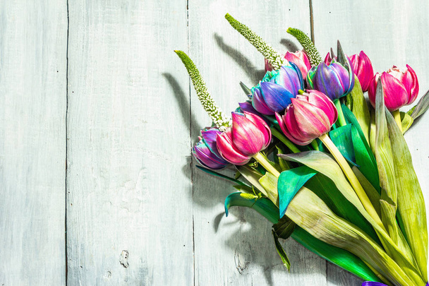 Букет необычных разноцветных тюльпанов. Свежие цветы, праздничный подарок. Старый деревянный серый стол. Современный жесткий свет, темная тень, место для текста - Фото, изображение