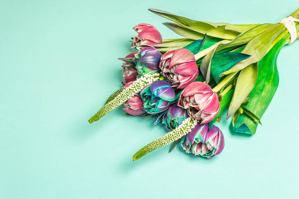 Un ramo de tulipanes multicolores inusuales. Flores frescas, concepto de regalo navideño. Fondo de color turquesa pastel, un lugar para el texto - Foto, imagen