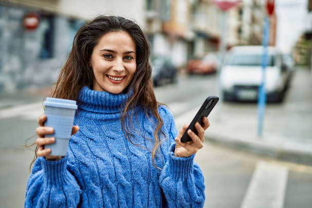 Młoda Latynoska kobieta pijąca kawę na telefon w mieście. - Zdjęcie, obraz