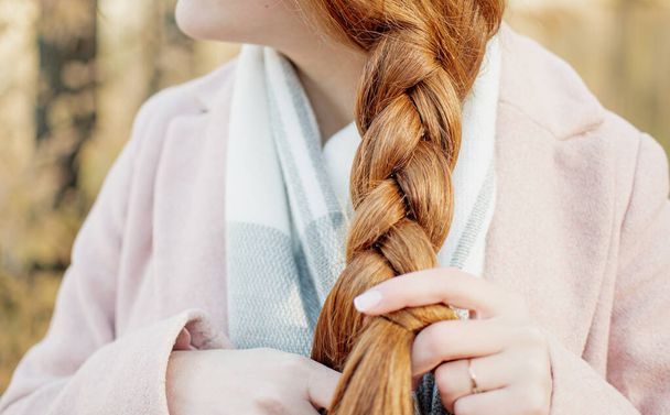 Una joven con el pelo rojo, hace su pelo, recoge su pelo para no interferir. Hermosa manicura. Paseo por la naturaleza - Foto, Imagen