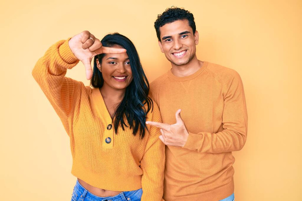 Beautiful latin young couple wearing casual clothes together smiling making frame with hands and fingers with happy face. creativity and photography concept.  - Photo, Image
