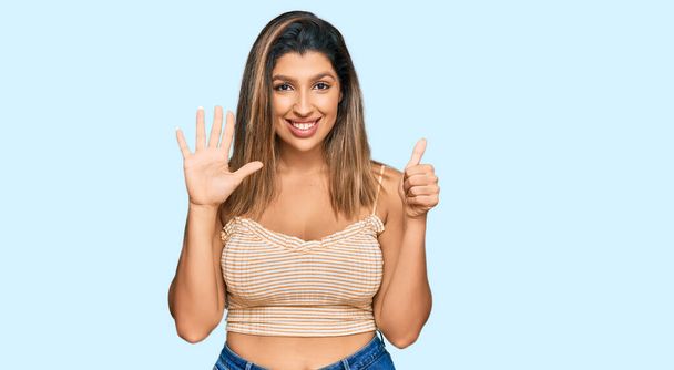 Beautiful brunette woman wearing casual clothes showing and pointing up with fingers number six while smiling confident and happy.  - Zdjęcie, obraz