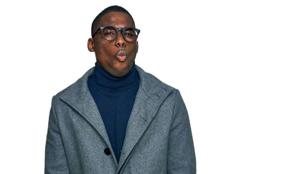 Young african american man wearing business clothes and glasses making fish face with lips, crazy and comical gesture. funny expression.  - Foto, afbeelding