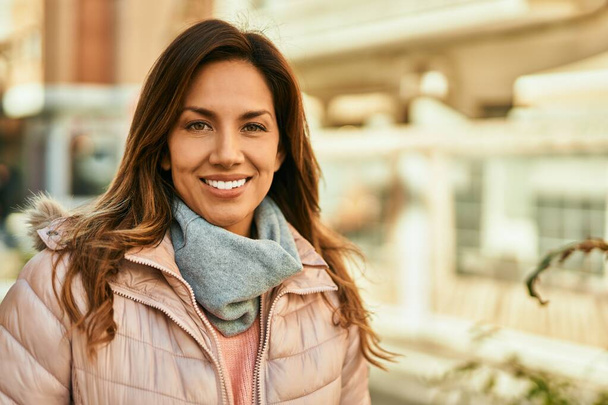 Молода іспаномовна жінка посміхається щаслива стоячи в місті
. - Фото, зображення