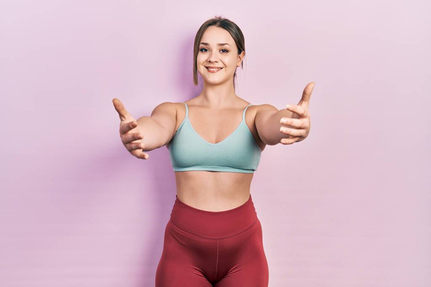 Young hispanic girl wearing sportswear looking at the camera smiling with open arms for hug. cheerful expression embracing happiness.  - Foto, immagini