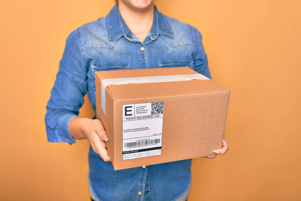 vrouw met kartonnen doos en pakket op kleur achtergrond - Foto, afbeelding
