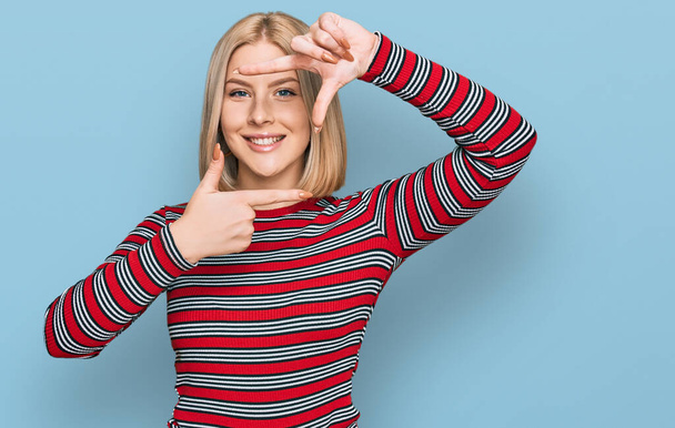 Young blonde woman wearing casual clothes smiling making frame with hands and fingers with happy face. creativity and photography concept.  - Photo, Image