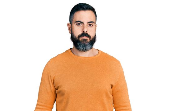 Spanyol férfi szakállal, alkalmi téli pulóvert visel, komoly arckifejezéssel. egyszerű és természetes nézi a kamerát.  - Fotó, kép
