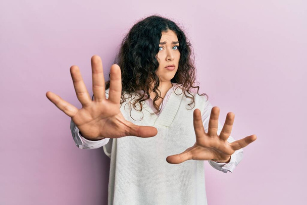 Junge brünette Frau mit lockigem Haar trägt lässige Kleidung tun Stop-Geste mit Handflächen, wütend und Frustration Ausdruck  - Foto, Bild