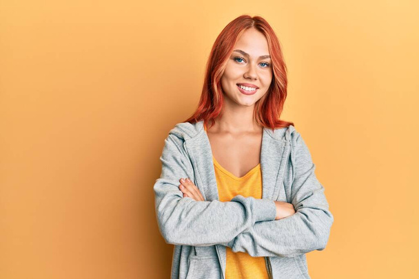 Fiatal gyönyörű vörös hajú nő alkalmi sportos pulóvert visel boldog arc mosolyogva keresztbe tett karokkal nézi a kamerát. pozitív személy.  - Fotó, kép