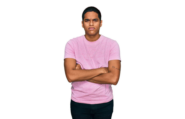Mladý pohledný hispánec v nenucené růžové tričko skeptický a nervózní, nesouhlasný výraz na tváři se zkříženýma rukama. negativní osoba.  - Fotografie, Obrázek