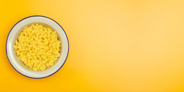 Nudelbanner Hintergrund. Mac and Cheese Pasta auf gelbem Hintergrund. Italienische Pasta nach amerikanischem Vorbild mit Käse. - Foto, Bild
