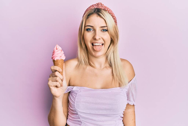 Jovem caucasiana segurando sorvete colando a língua feliz com expressão engraçada.  - Foto, Imagem