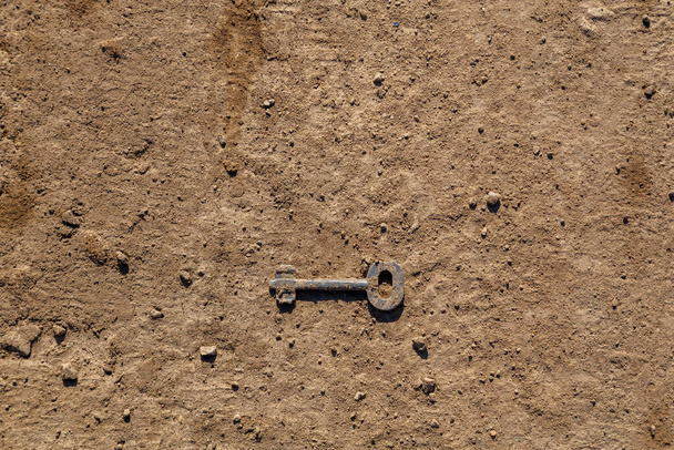 llave vieja en la superficie seca del suelo de la suciedad bajo luz solar directa - Foto, Imagen