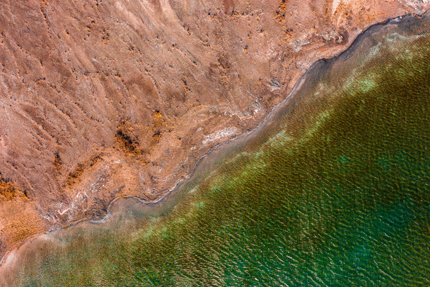 Widok z lotu ptaka na skaliste wybrzeże z turkusową falującą wodą. - Zdjęcie, obraz