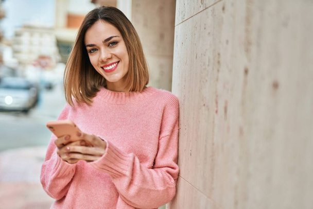 Young caucasian girl smiling happy using smartphone at the city. - Foto, Bild