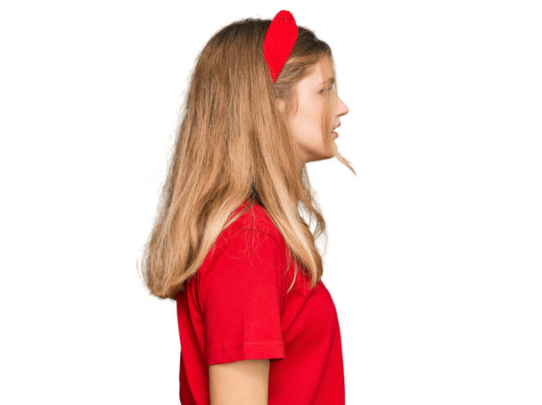 Όμορφη νεαρή καυκάσια κοπέλα φορώντας casual κόκκινο t πουκάμισο κοιτάζοντας προς τα πλάγια, να χαλαρώσετε προφίλ ποζάρουν με φυσικό πρόσωπο με αυτοπεποίθηση χαμόγελο.  - Φωτογραφία, εικόνα