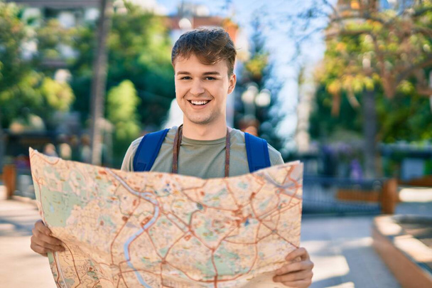 Молодий кавказький турист посміхається щасливий тримає карту в місті
. - Фото, зображення
