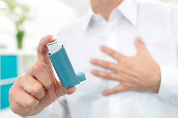 Man using blue asthma inhaler medication with breathing difficulties - Photo, image