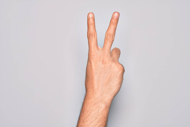 Käsi valkoihoinen nuori mies näyttää sormet yli eristetty valkoinen tausta laskenta numero 2 osoittaa kaksi sormea, eleiden voitto ja voittaja symboli - Valokuva, kuva