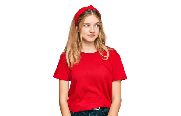 Belle jeune fille caucasienne portant casual t-shirt rouge souriant regardant sur le côté et regardant loin en pensant.  - Photo, image
