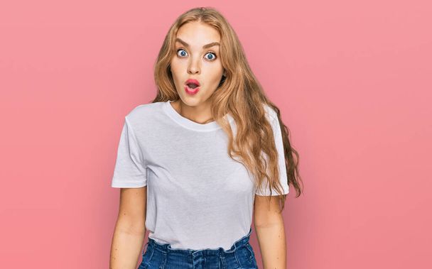 Young caucasian girl wearing casual white t shirt scared and amazed with open mouth for surprise, disbelief face  - Φωτογραφία, εικόνα