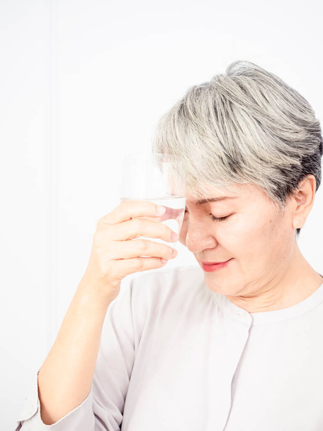 edad, cuidado de la salud y el concepto de las personas - feliz mujer de edad avanzada asiática con un vaso de agua en casa - Foto, imagen