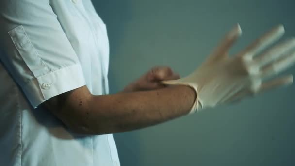 Медсестра надевает латексные перчатки во время пандемии коронавируса. Закрытие.   - Кадры, видео