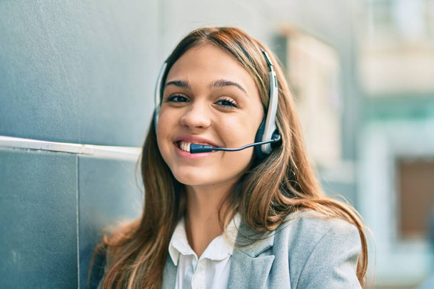 Joven latino call center aget chica sonriendo feliz usando auriculares en la ciudad. - Foto, Imagen