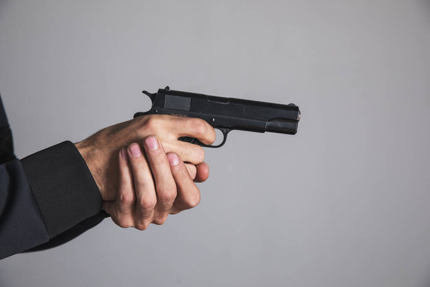 a man holding a black pistol in his hand threatening - Zdjęcie, obraz