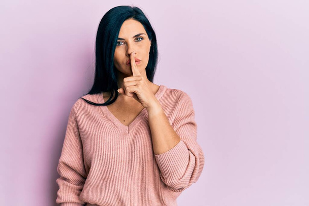 Junge kaukasische Frau in lässiger Kleidung, die mit dem Finger auf den Lippen um Ruhe bittet. Schweigen und geheimes Konzept.  - Foto, Bild