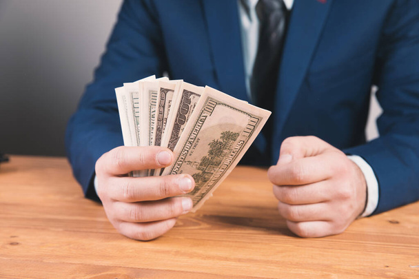 мужчина, сидящий с деньгами в руке - Фото, изображение