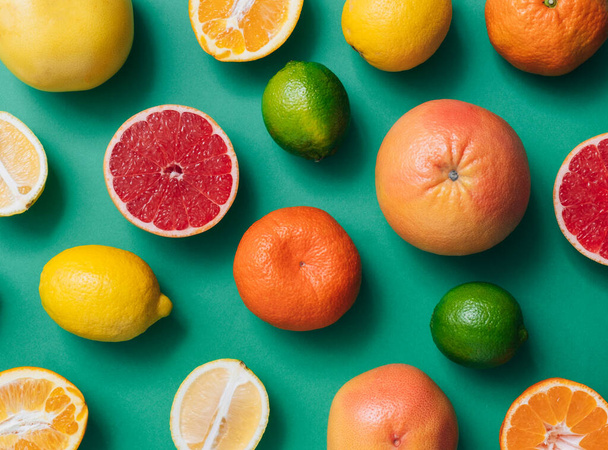 Frutas cítricas em mesa verde com espaço de cópia. Citrinos frescos, incluindo limão, limões, laranja, toranja amarela, toranja rosa e tangerinas sobre fundo verde com espaço vazio - Foto, Imagem
