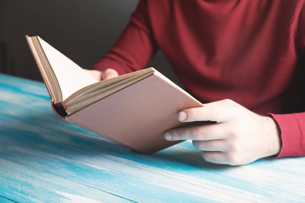 молодий хлопець читає книгу на столі
 - Фото, зображення