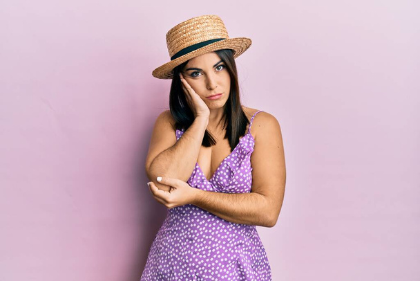 Young brunette woman wearing summer dress and hat thinking looking tired and bored with depression problems with crossed arms.  - Фото, изображение